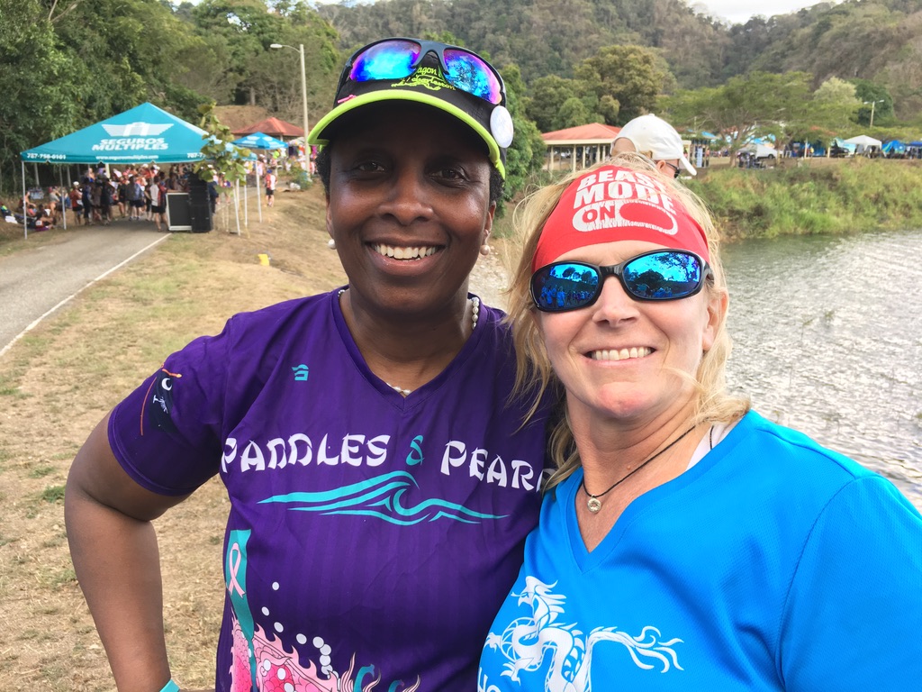 Two people smiling in front of the water