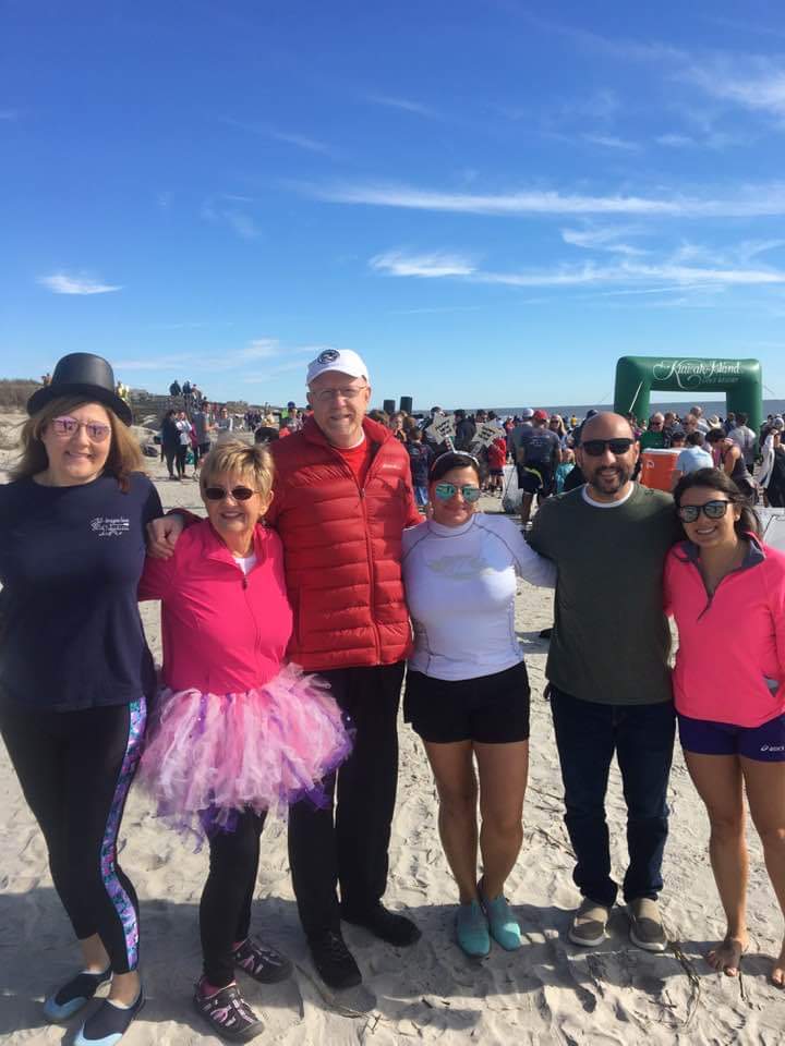 Group of people smiling on beach at Winter Wellness 2024 polar plunge