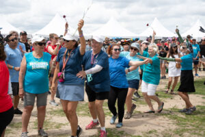 Group of people dancing and holding flowers at 2024 Dragon Boat Fesitval