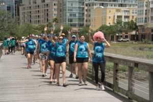 Group of people in matching tie dye shirts walking down the dock to their boat