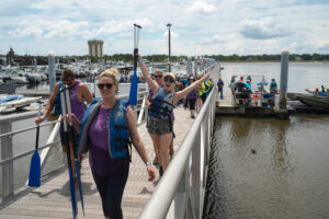 People wearing life jackets and holding oars on the dock