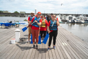 Group of people on the dock wearing their life jackets and pretending to row their oars