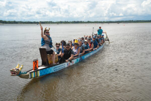 Group of people on the dragon boat in the water smiling and preparing to race