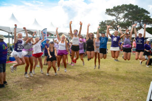 Group of women wearing purple and jumping in the air