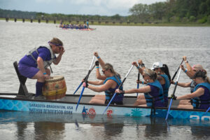 Man on the front of the dragon boat instructing his team when to paddle