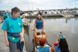 Woman at front of dragon boat with her drum preparing to lead her team