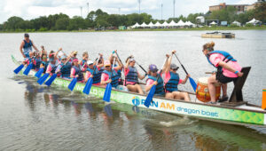 Dragon boat team with pink shirts and. blue life jackets paddling in the water