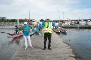 Man in yellow vest and orange sticks directing traffic on the dock
