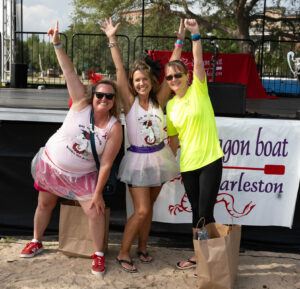 Three women posing in front of the stage as the 2024 Top Fundraisers