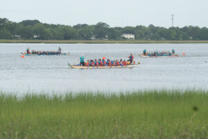 Three boats in the water racing at 2024 Dragon Boat Festival